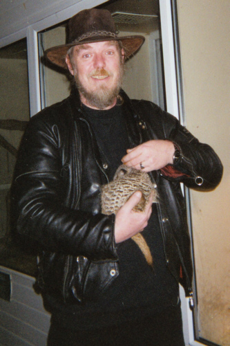 Bill cuddling Timone, a tame meerkat